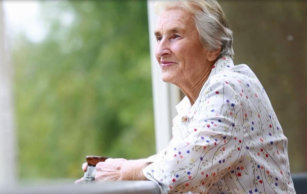 Female holding a cup of tea on a balcony looking away at something