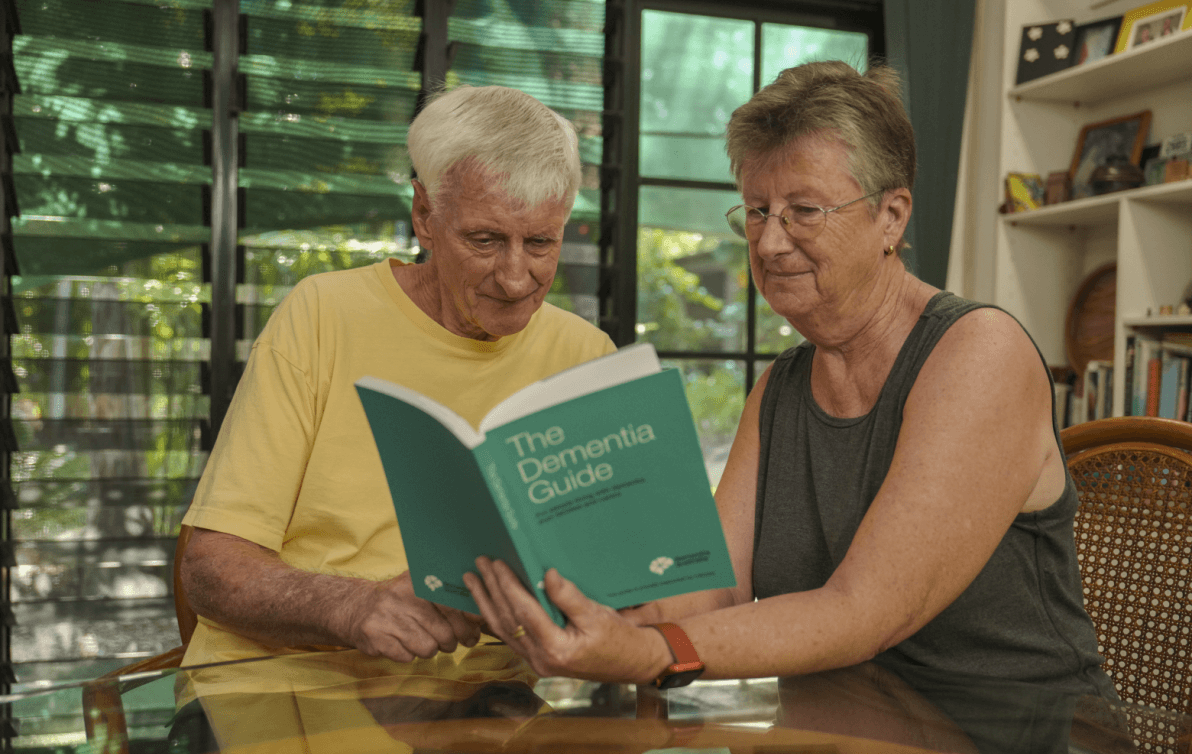 A man and woman sitting at a table reading