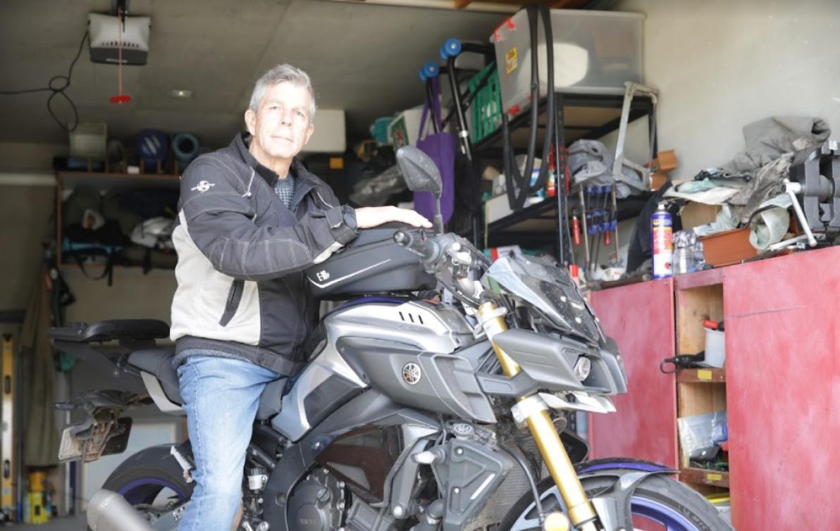 A man wearing motorcycle safety clothing sitting on his bike in his garage