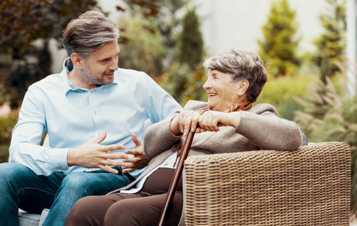 Elderly lady sitting in the garden with family member