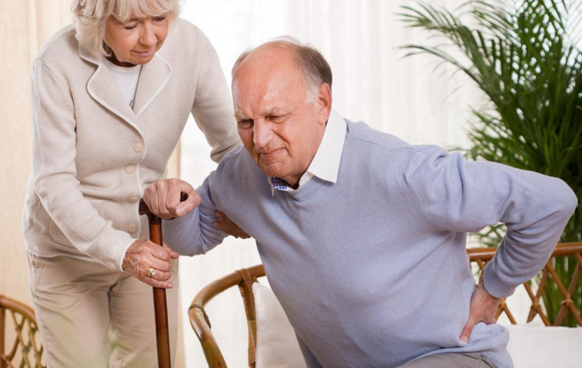 Elderly man with back pain being assisted by his wife