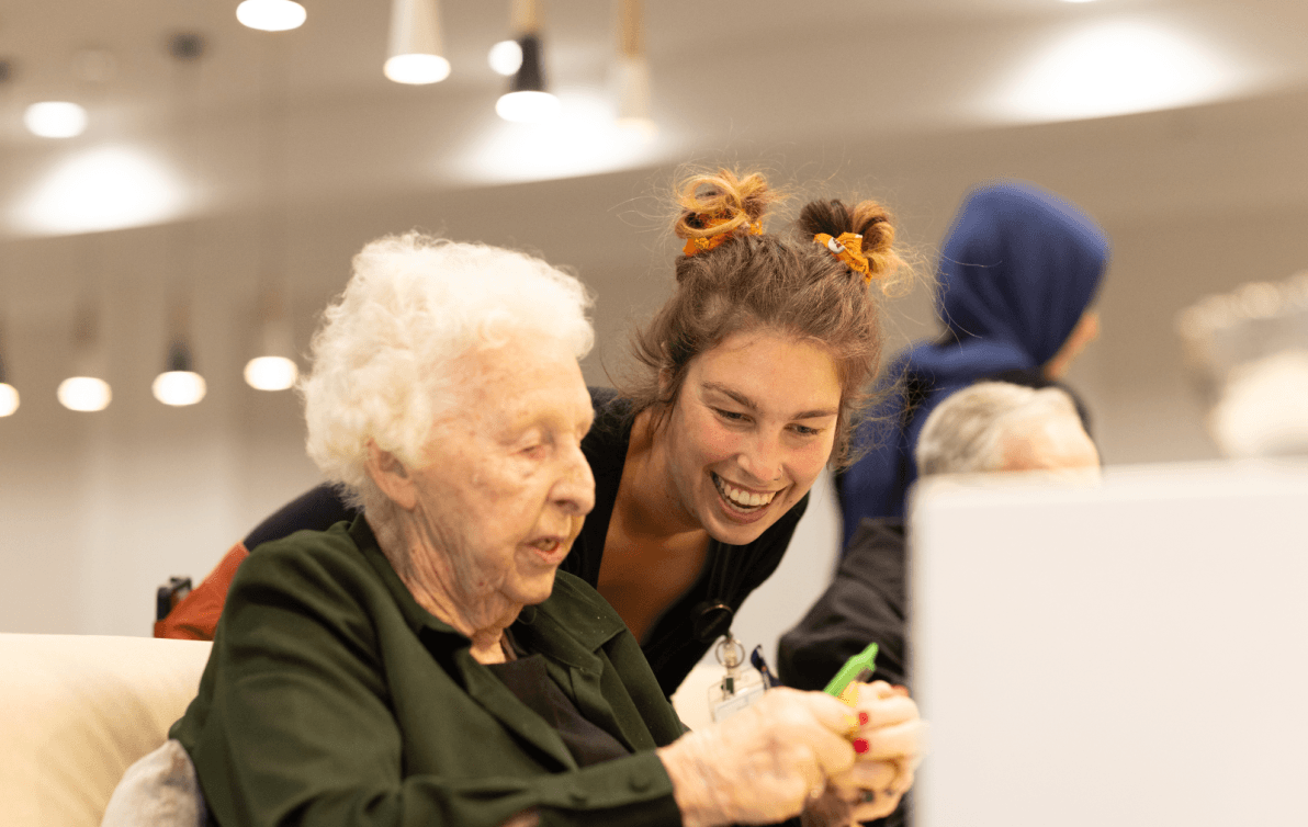 Carer assisting elderly lady with recreational activities 