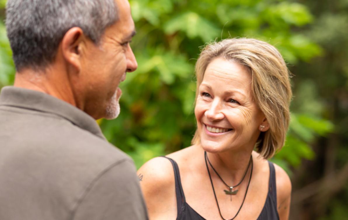 A man and a woman smiling outside.