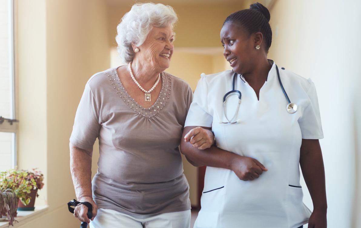 An age care durse assisting a female to walk