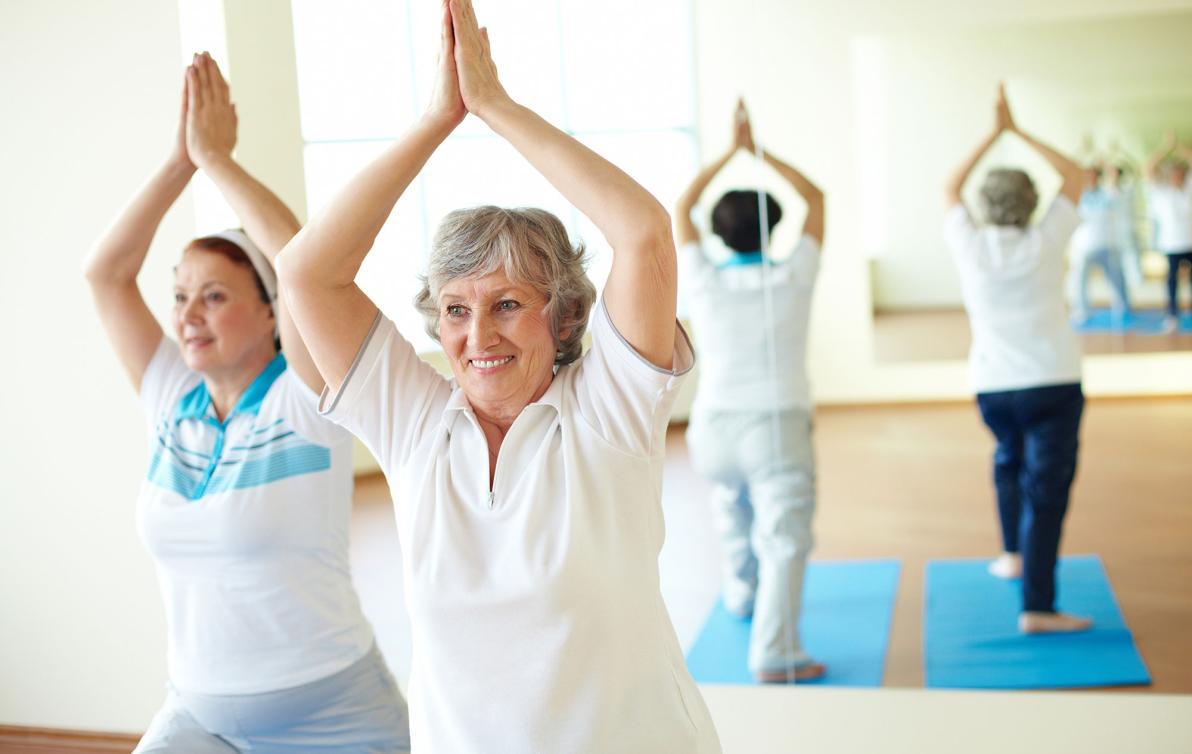 Two women doing exercise with their hands above their head in a yoga like pose