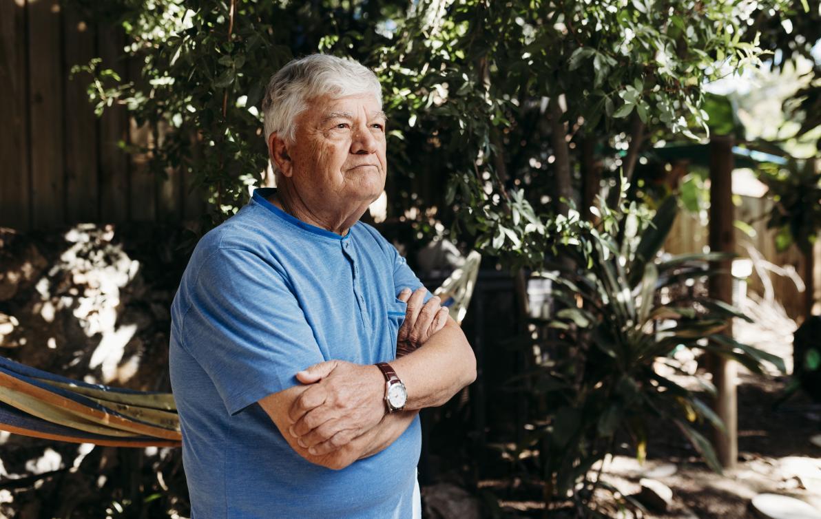 Image of a man in a garden wearing a blue shirt looking into the distance 