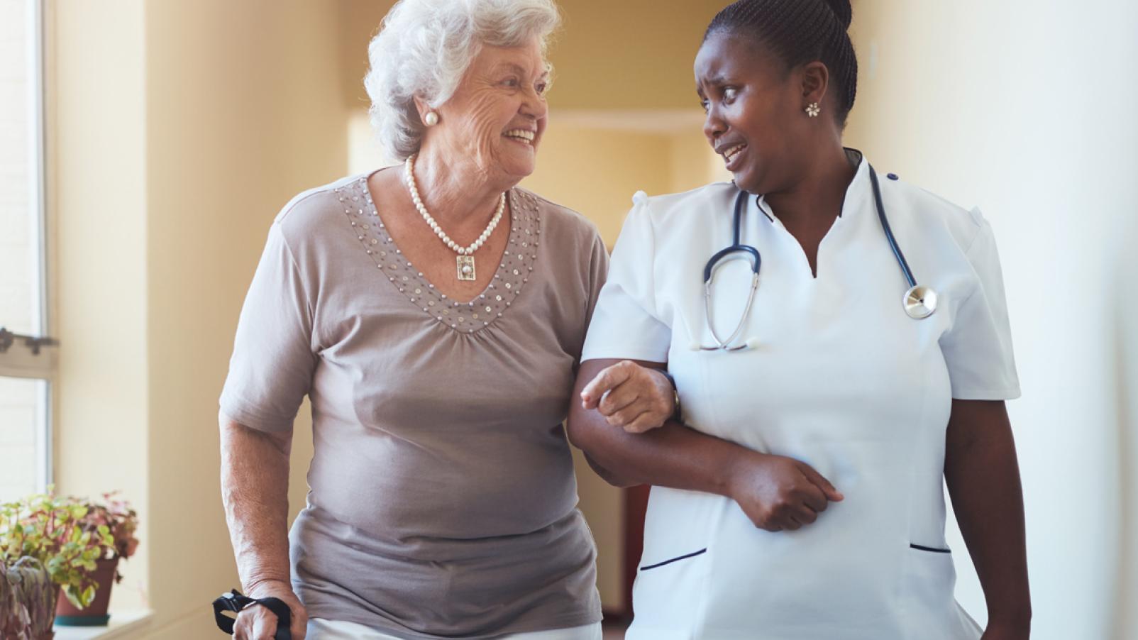 An age care durse assisting a female to walk