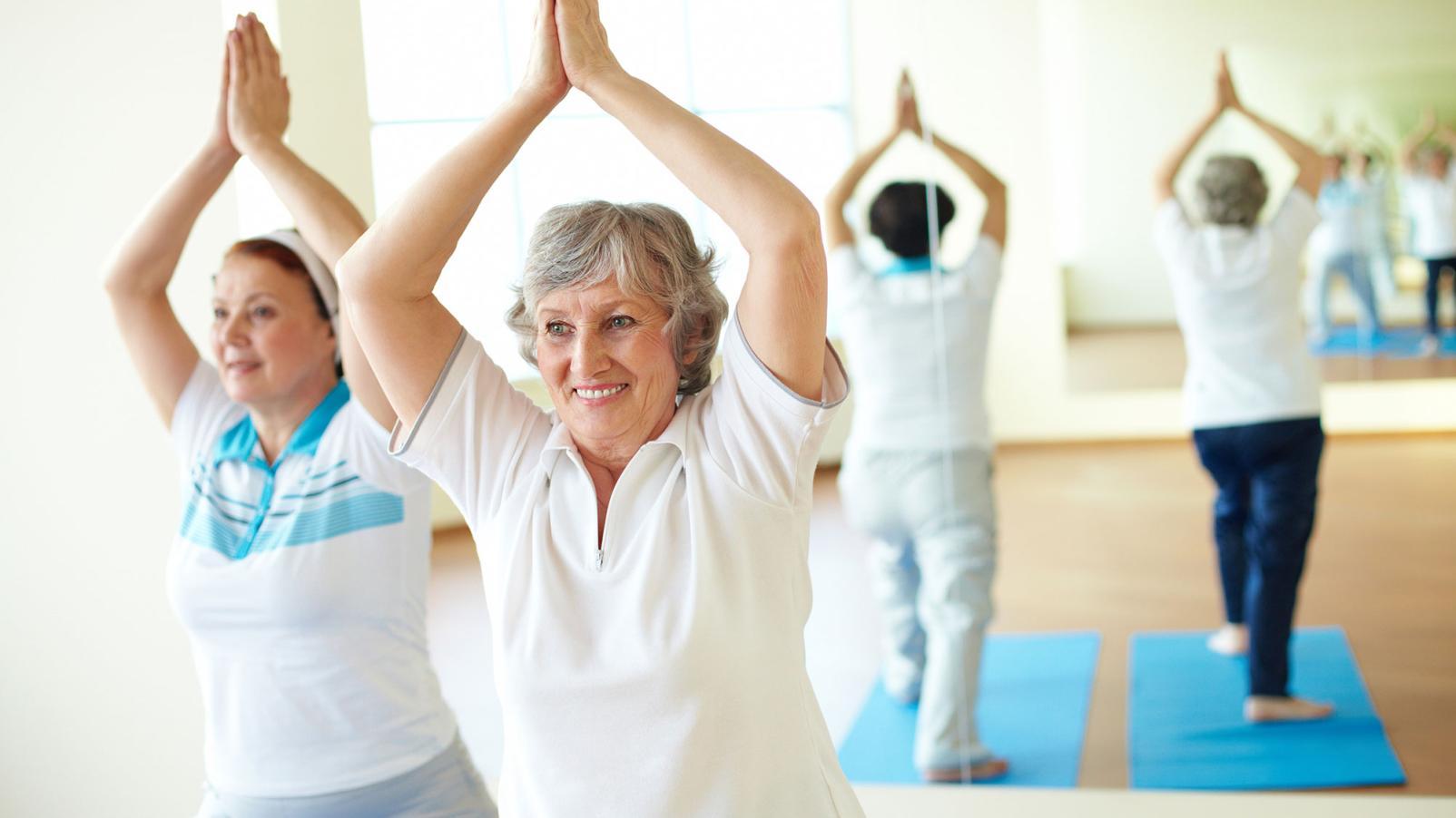 Two women doing exercise with their hands above their head in a yoga like pose