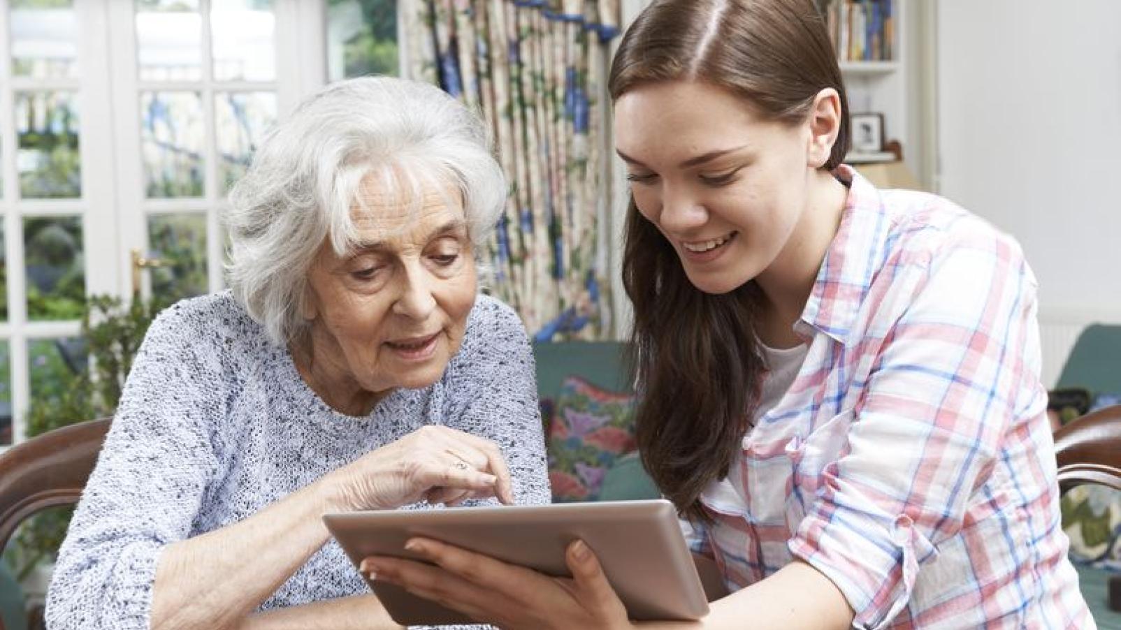 Two women look together at the screen of an iPad.