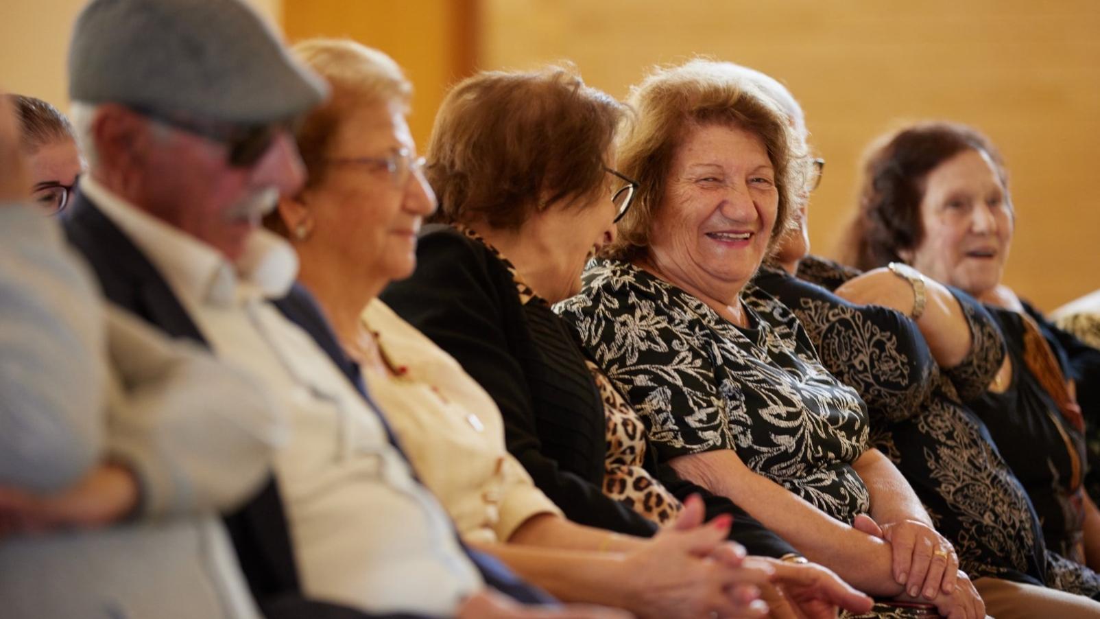 A row of people sitting, talking and laughing.