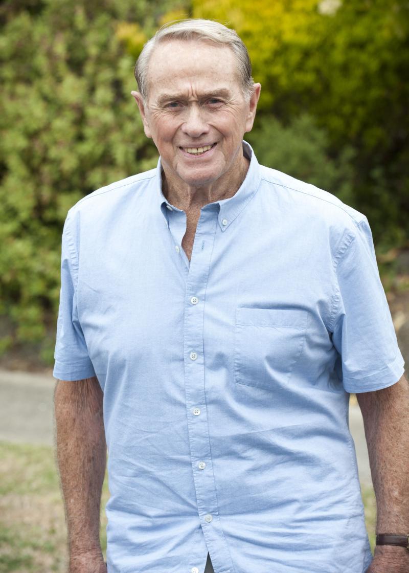 Terence Donovan outside looking at the camera, smiling and wearing a light blue shirt