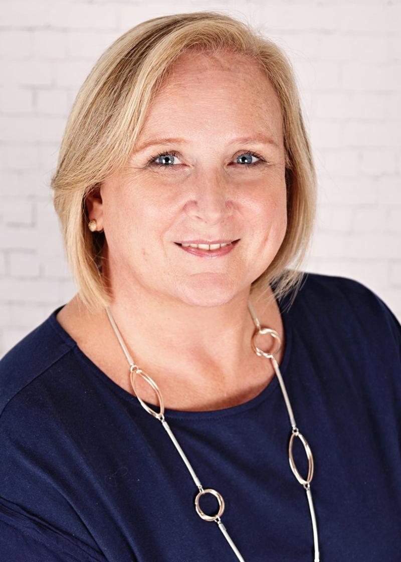 Margaret MacAndrews looking at the camera smiling wearing a navy blue top.