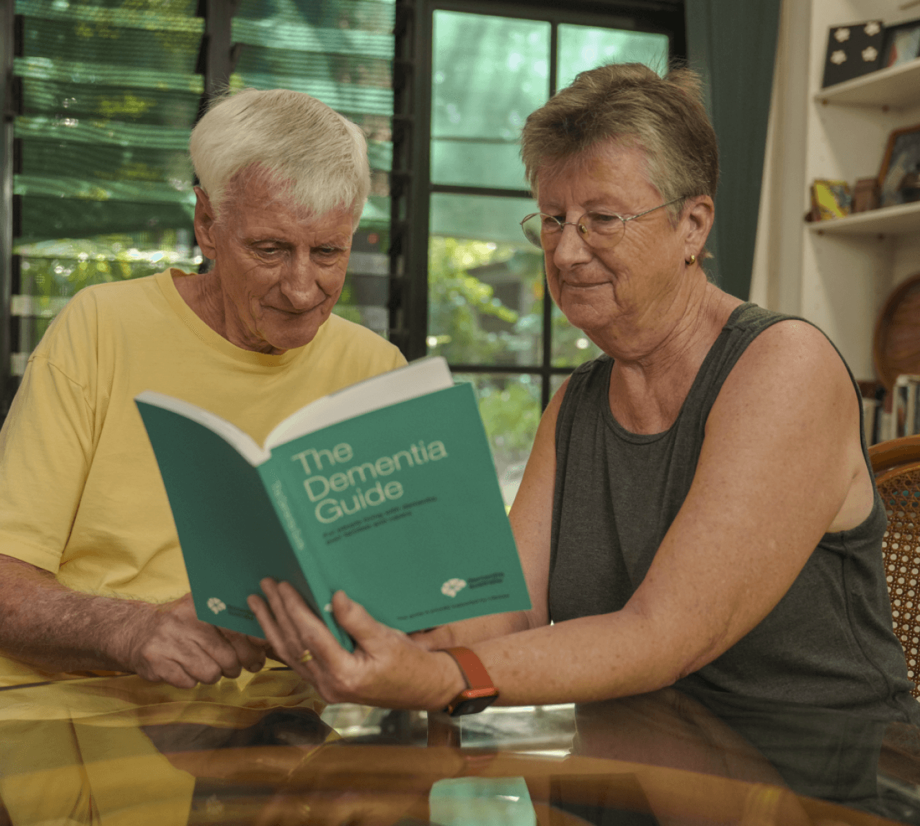 A man and woman sitting at a table reading