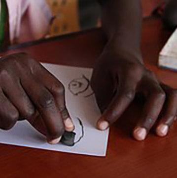 A close up photo of someone drawing with a black crayon